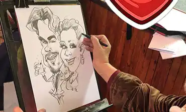 Malý chlapec sa radostne usmieva a v rukách drží svoju čerstvo nakreslenú karikatúru zo svadobnej oslavy.